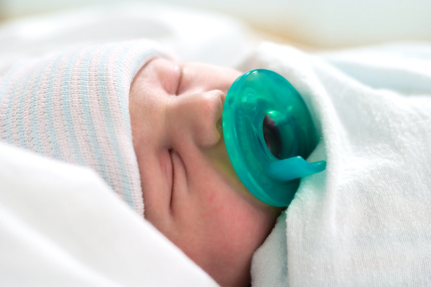 Foto choc di una neonata di 2 mesi con il ciuccio attaccato alla bocca 
