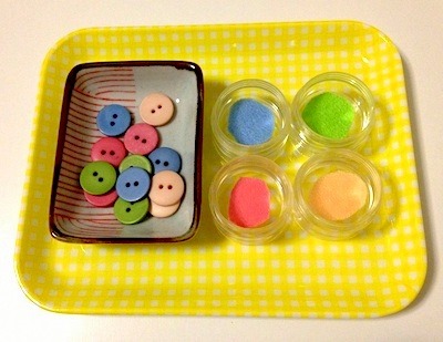 Metodo Montessori a casa: esempio di attività. Qui il bambino dovrà portare nelle ciotole i bottoni selezionandoli in base al colore. Affinerà la competenza dei colori.