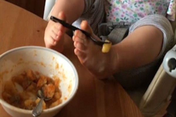 bambina senza le braccia impara a mangiare con i piedi